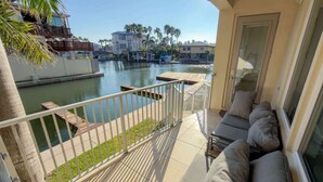 Een balkon met uitzicht op een jachthaven, een zwembad en omliggende gebouwen.