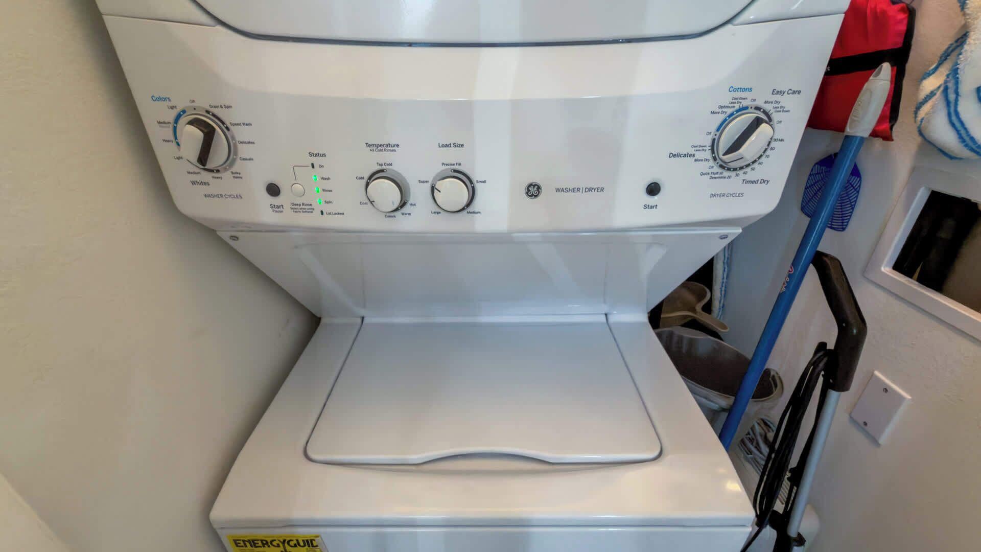 Vista frontal de uma máquina de lavar e secar embutida, com botões de controle para temperatura, tamanho da carga e seleção de ciclo.