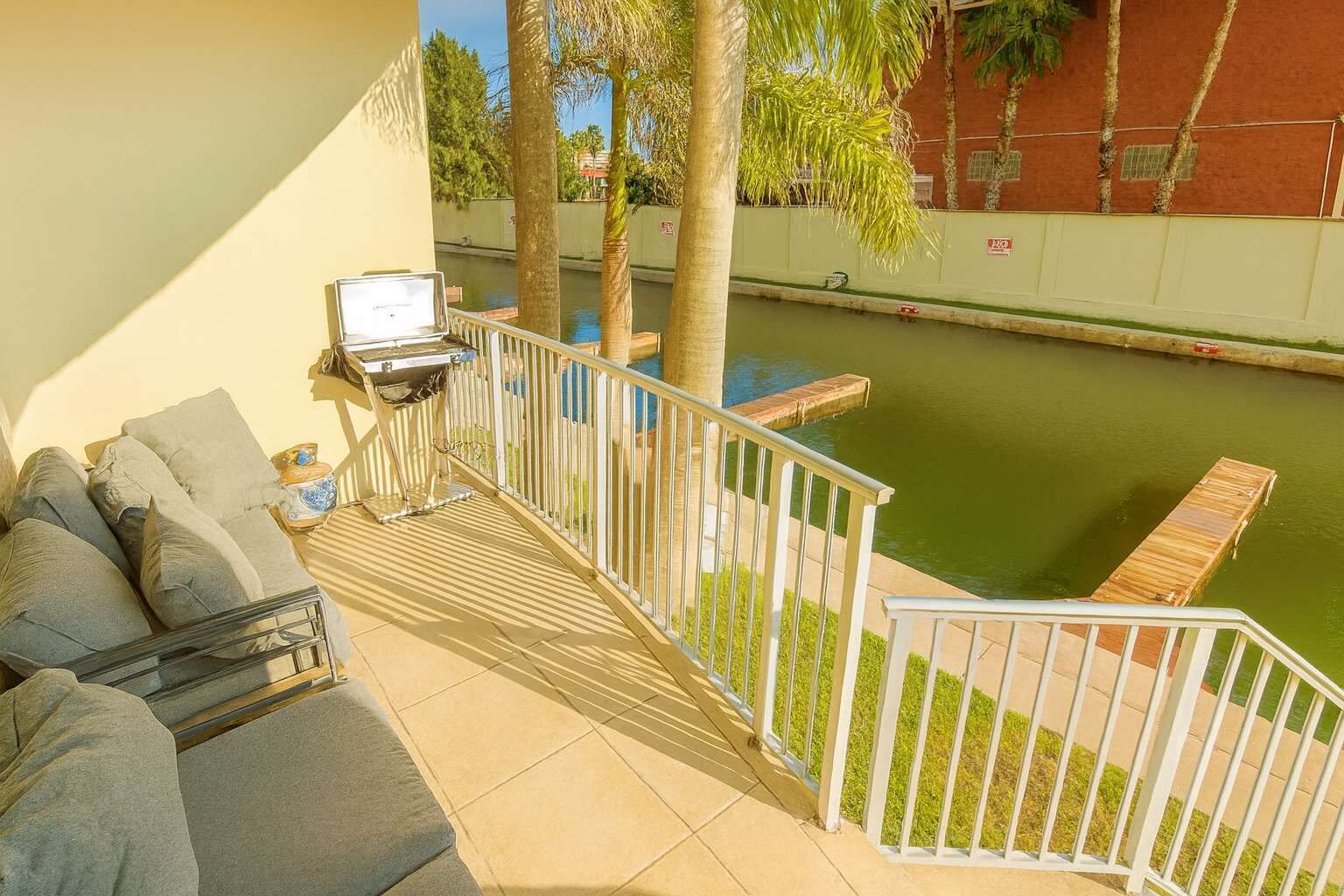 A balcony with a grill, outdoor seating, and a view of a water body.