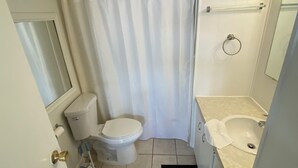 Ein kleines Badezimmer mit Toilette, Waschbecken und Duschvorhang.