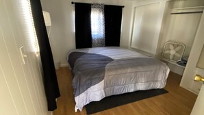 Ein kleines Schlafzimmer mit Bett, Deckenventilator und einem Vorhangfenster.
