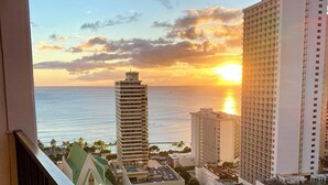 A high-rise hotel with a view of the sunset over the ocean, featuring multiple floors and a prominent building in the foreground. - Waikiki Banyan Ocean View Suite, High Floor Remodeled, AC & Free Parking (Honolulu)