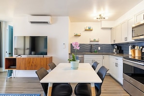 A modern kitchen with a dining area, built-in appliances, and decorative shelves. - Waikiki Banyan Ocean View Suite, High Floor Remodeled, AC & Free Parking (Honolulu)