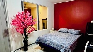A bedroom with a bed, a ceiling fan, a window, and a red wall. - Cozy 1-bedroom house in beautiful Grecia with AC (Grecia)