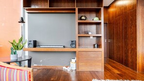 Una habitación moderna con escritorio integrado, estanterías de madera y una pequeña mesa con planta en maceta.