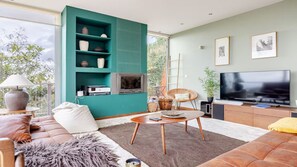 Un salon moderne avec un mur d’accent de couleur turquoise, un téléviseur à écran plat, un canapé confortable et une table basse.