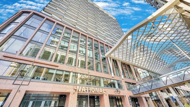 Un bâtiment moderne, reconnaissable à son grand panneau indiquant « NATIONAL », à ses larges fenêtres et à sa structure de toit en verre originale.