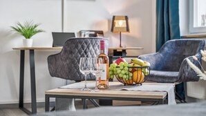 Een moderne woonkamer met een eettafel, een bank, een aan de muur bevestigde televisie en een lamp.