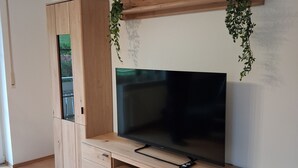 Eine Holzmultimediamöbel mit Flachbildfernseher, Schubladen und hängenden Pflanzen.