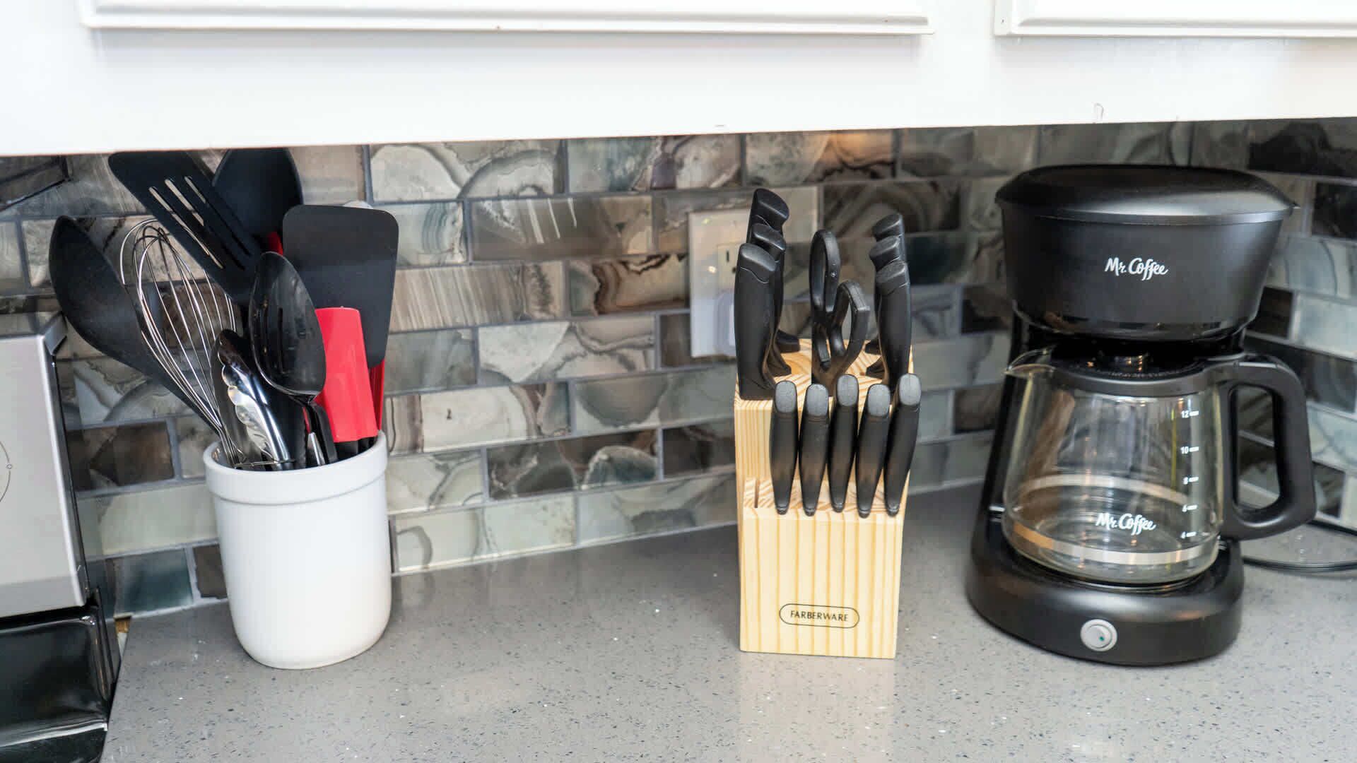 A kitchen counter with a coffee maker, a utensil holder, and a knife block.