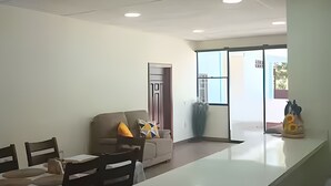 A modern kitchen with a white countertop, wooden chairs, and a sofa with colorful cushions. - Private Family Country Home in Usulutan, El Salvador (Usulutan)