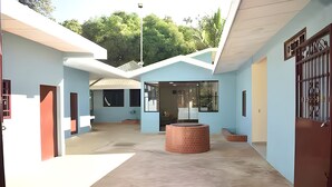 A spacious courtyard with a central brick structure, surrounded by light blue walls and a covered area with a metal gate. - Private Family Country Home in Usulutan, El Salvador (Usulutan)