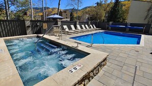 A hot tub and a swimming pool with lounge chairs, surrounded by a wooden fence and a mountain view. - Free Parking, Pool, Hot Tub, near Gondola | W301 (Vail)