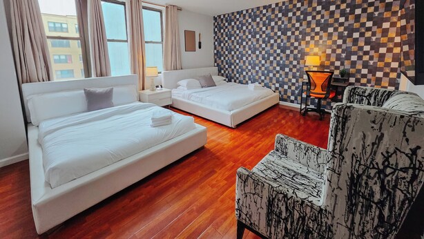 Une chambre d’hôtel avec deux lits, un bureau, une chaise et un mur décoré de motifs.