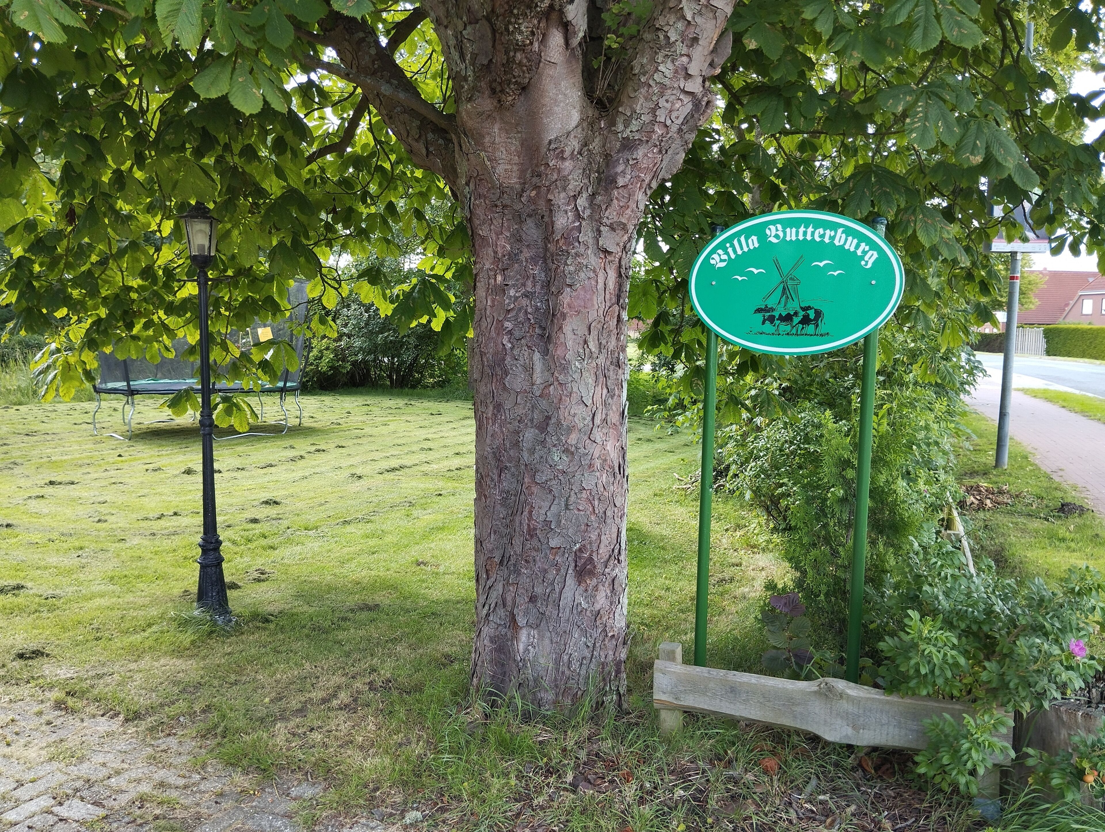 Ein Park mit einem Schild, das 'Villa Butteburg' zeigt, und einem Baum.