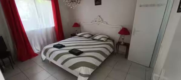 Quarto com cama, duas mesas de cabeceira, um lustre e um guarda-roupa.