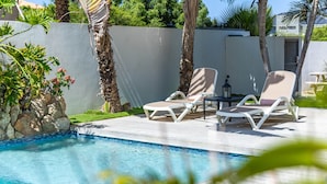Une piscine avec des chaises longues et un mur en pierre.