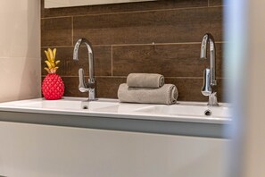 Ein Badezimmer mit zwei Waschbecken, einem Handtuch und einer Ananas-Dekoration.