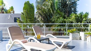 Une terrasse sur le toit avec deux chaises longues, une petite table et deux bouteilles de bière.