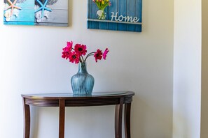 Ein runder Holztisch mit einer Glasvase und pinkfarbenen Blumen.