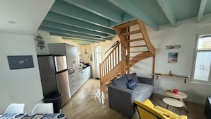 A modern kitchen with a built-in refrigerator, wooden staircase, and a dining area with a table and chairs. - House just a stone's throw from the sea (Saint-Gilles-Croix-de-Vie)