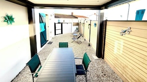An enclosed patio with a table and chairs, a covered ceiling, and a wooden fence. - House just a stone's throw from the sea (Saint-Gilles-Croix-de-Vie)