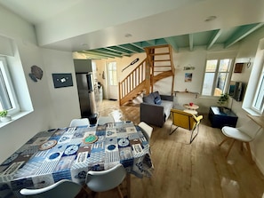 Un vaste espace de vie comprenant une table à manger, des chaises, un canapé et un escalier menant à un autre niveau.