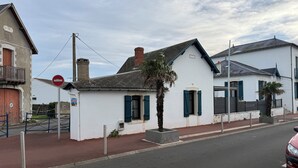 A white building with green shutters and a red door, located on a street with a red curb and a no-entry sign. - House just a stone's throw from the sea (Saint-Gilles-Croix-de-Vie)