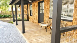 A wooden deck with a covered seating area, a gravel path, and a wooden fence. - The Downtown Cedar (Ocean Springs)
