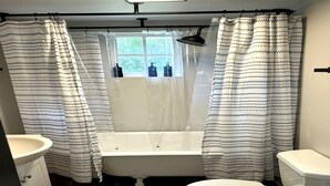 A bathroom with a bathtub, toilet, and sink. - The Downtown Cedar (Ocean Springs)