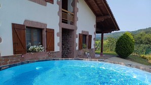 Ein Poolbereich mit einer Steinmauer, Holzläden und Blick auf die Landschaft.