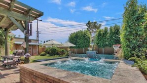 Ein Garten mit Whirlpool, Basketballkorb und einer Terrasse mit Sitzgelegenheiten.