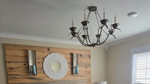 Ein Schlafzimmer mit einem großen Bett, einem Holzkopfende, einer Chandelüstere und einem Fenster mit Jalousien.