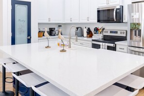 A modern kitchen with white cabinetry, stainless steel appliances, and a central island with a faucet and decorative birds. - Steps to Beach Private Pool 2 Big Levels (South Padre Island)