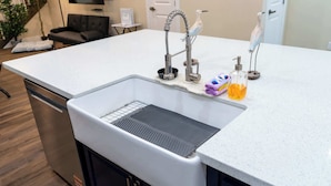 A kitchen with a built-in stainless steel sink, a dish drying rack, and a small countertop area with a bottle of dish soap and a towel. - Steps to Beach Private Pool 2 Big Levels (South Padre Island)