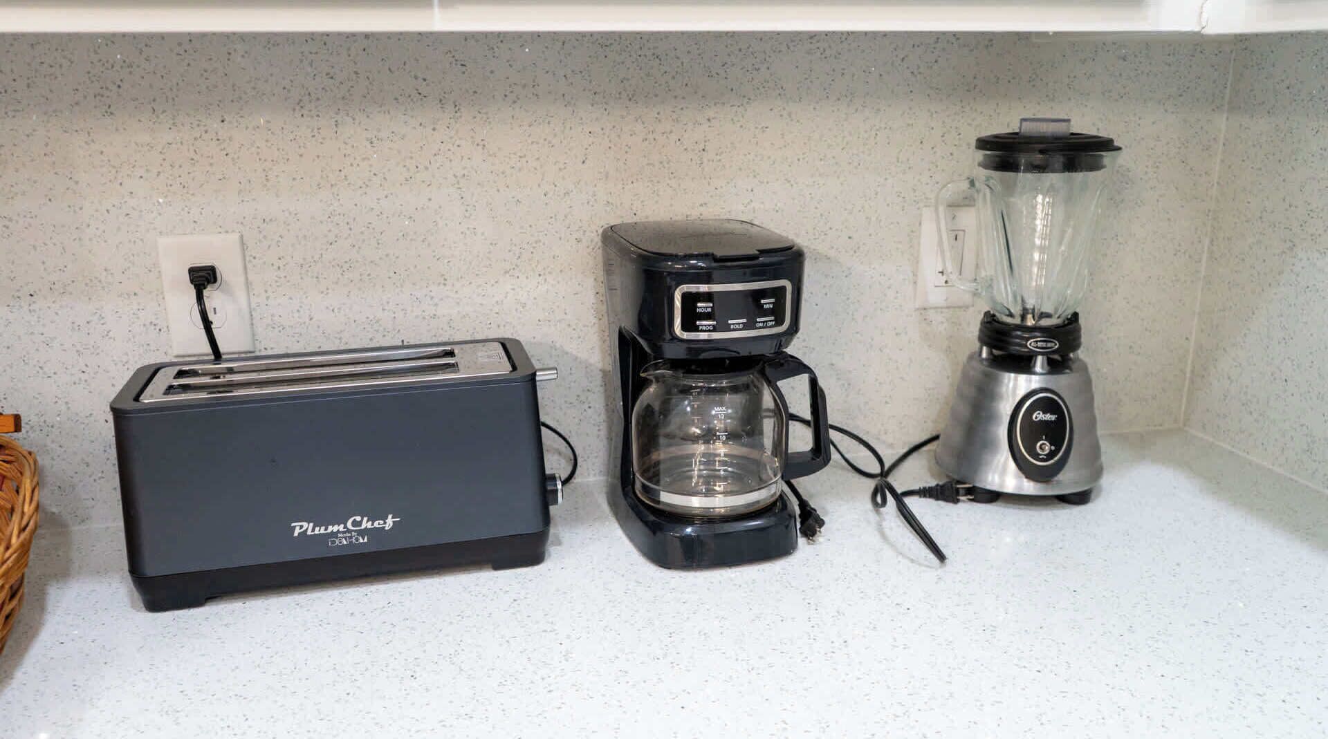 A kitchen with a toaster, a coffee maker, and a blender on a countertop.