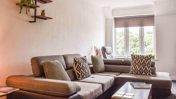 Ein modernes Wohnzimmer mit einem Ecksofa, einem Couchtisch und einem Fenster mit Blick.