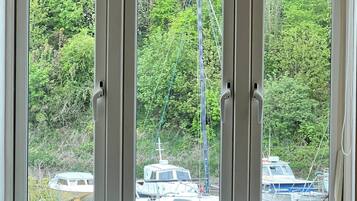 Ein Fenster mit Blick auf eine Marina, Boote und üppiges Grün.