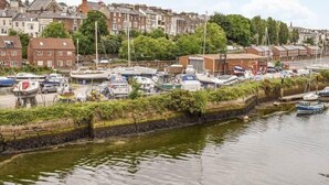Uma marina com barcos atracados, rodeada por edifícios residenciais e vegetação.
