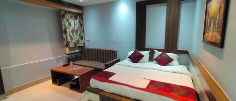 Une chambre d’hôtel comprenant un lit, un canapé, une petite table et un climatiseur fixé au mur.