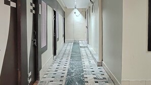 A hotel hallway with a patterned floor, doors on both sides, and a ceiling light. - Hotel Jay Deluxe (Sasaram)