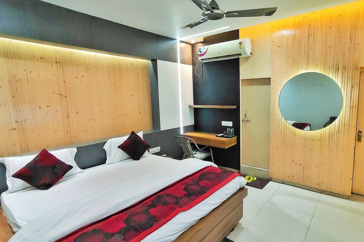 Ein Hotelzimmer mit Bett, Schreibtisch, Stuhl, Spiegel und Kleiderschrank.