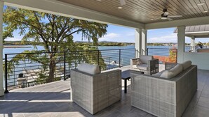 Un espacio al aire libre techado con mobiliario de mimbre, una mesa y vistas a un lago.