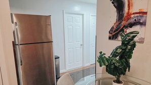 A kitchen with a stainless steel refrigerator, a trash bin, and a potted plant on a glass table. - Vale / King Bed / Elevator / Balcony / Ensuite (Philadelphia)