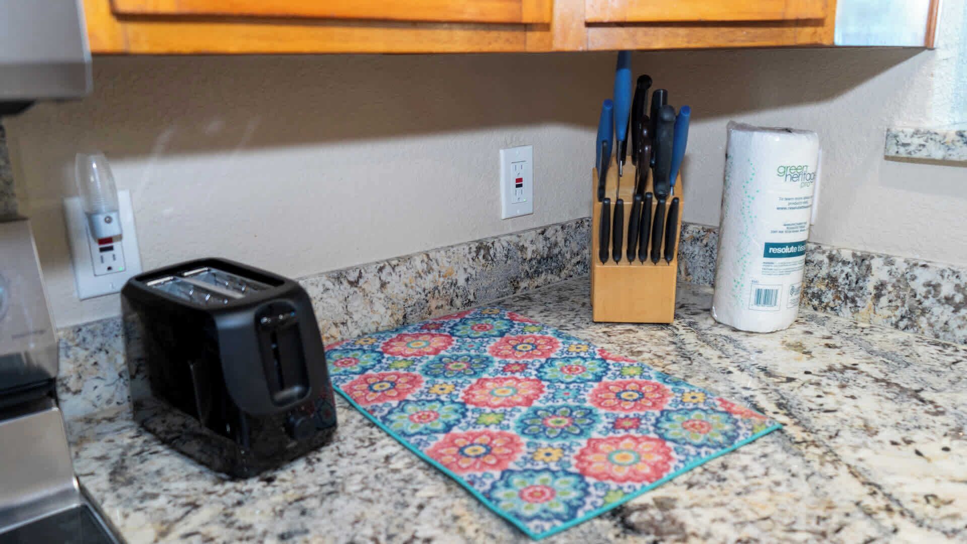 A kitchen counter with a toaster, a knife block, and a can of green tea.