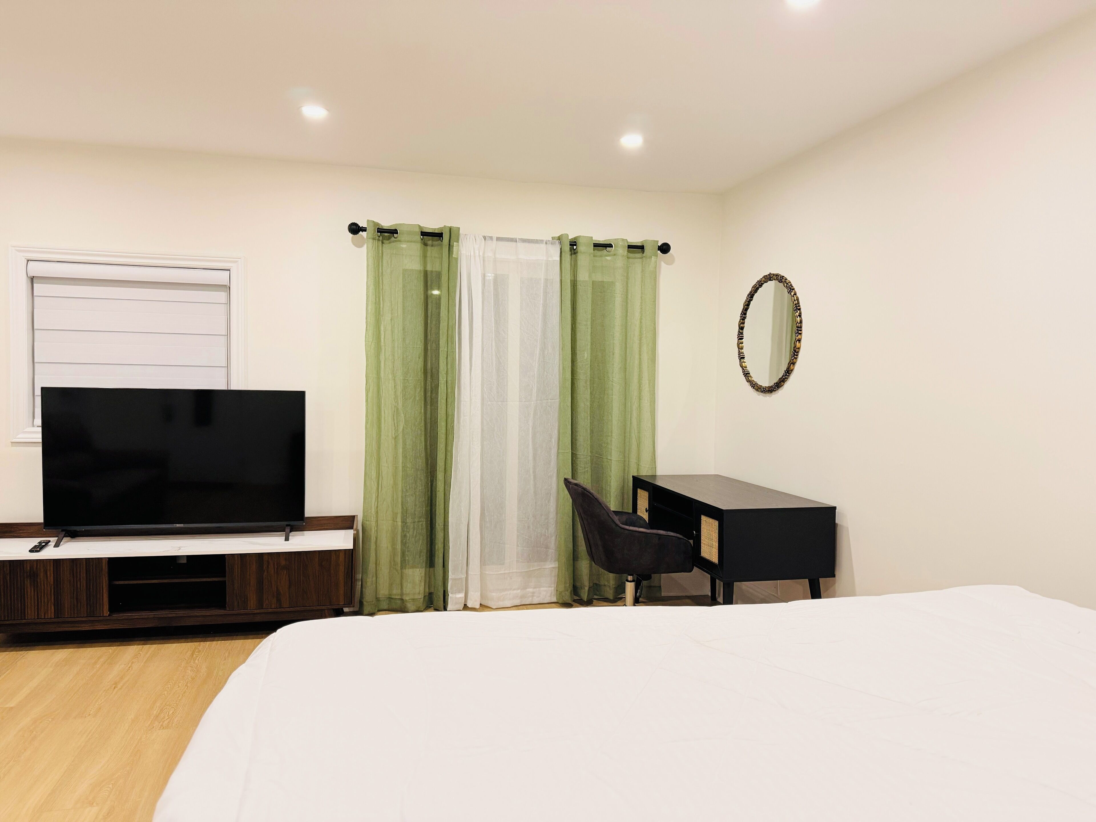 A hotel room with a bed, a TV, a desk, and a chair.
