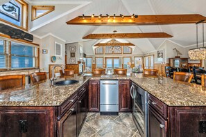 A spacious kitchen with a large island, wooden beams, and a view to the outside. - Oceanfront, elevator, pool, hot tub, walk to shops. Friday check in. (Kitty Hawk)