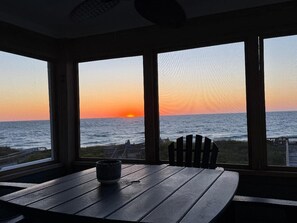 A room with a view of the sunset over the ocean, a wooden table, and a chair. - Oceanfront, elevator, pool, hot tub, walk to shops. Friday check in. (Kitty Hawk)