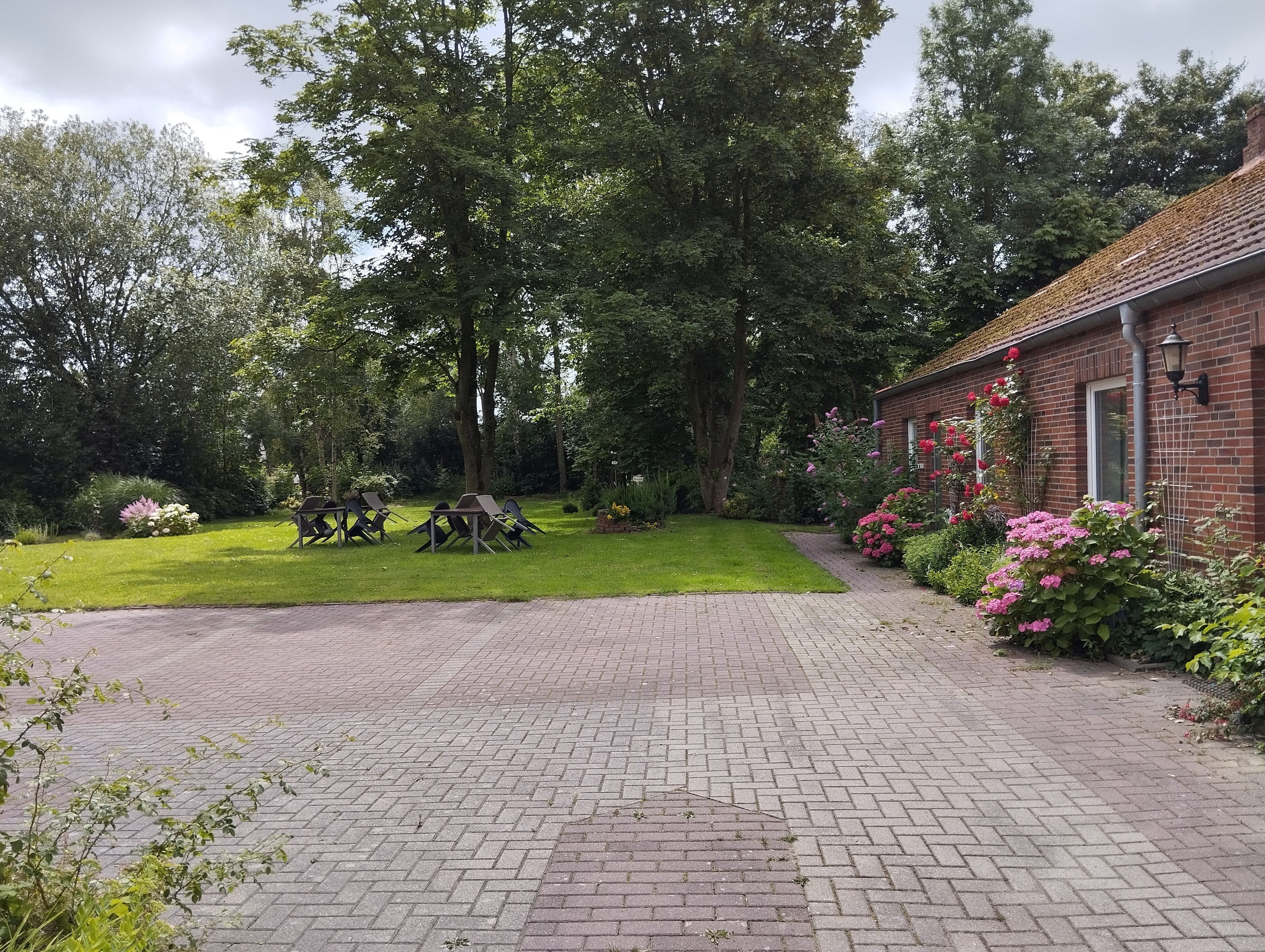 A brick building with a paved driveway leading to a grassy area with outdoor seating.