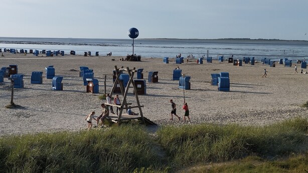 En strand med blå stolar och ett livräddartorn.